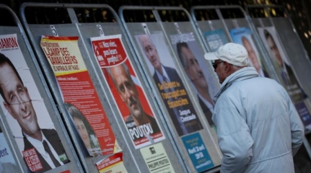 A man looks at campaign posters of the 11th candidates who run in the 2017 French presidential election in Enghien-les-Bains, near Paris, France April 19, 2017.